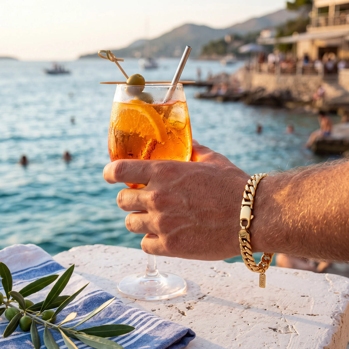 Cuban link bracelet, gold, worn on a terrace by the sea
