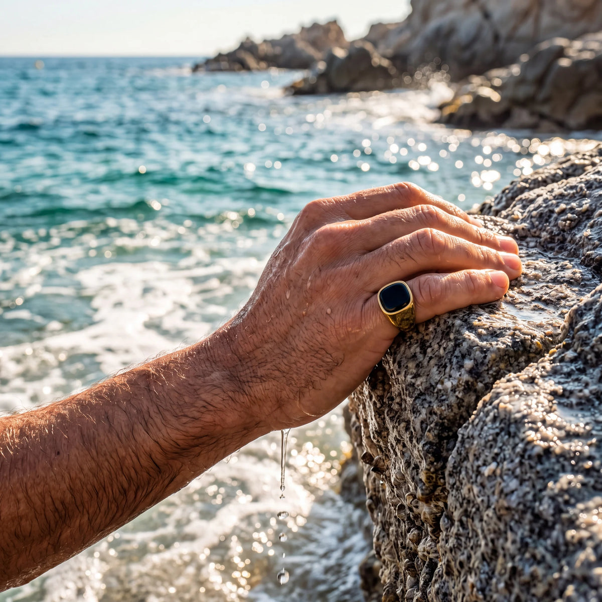 Black stone signet ring, gold, worn at the sea